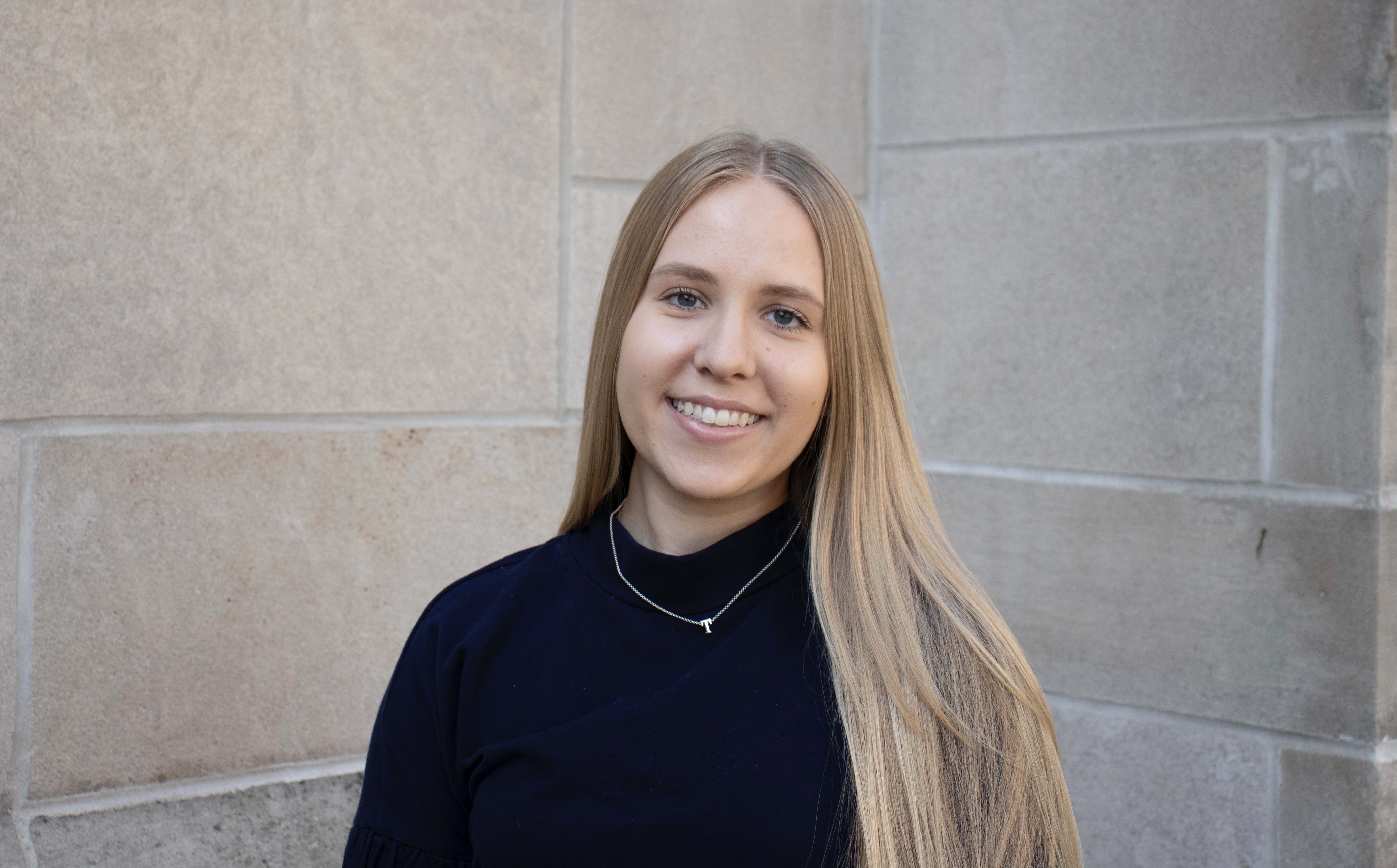 Abby Welch wearing a navy blue shirt in front of limestone.